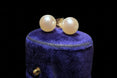 The Vintage Vault vintage 14K yellow gold pearl stud earrings with a polished finish displayed on a blue velvet box.