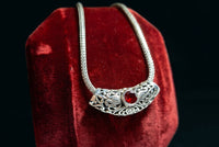 The Vintage Vault vintage sterling silver necklace featuring a polished Bali style sliding pendant with a red garnet.